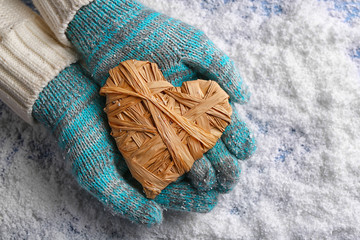 Fototapeta na wymiar Female hands in mittens with decorative heart on snow background