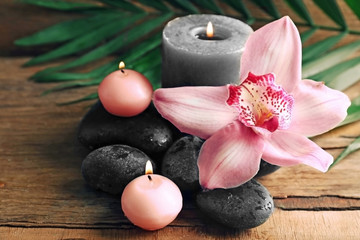 Fototapeta na wymiar Spa stones with beautiful flowers and candles on wooden background