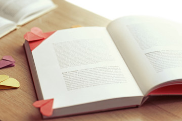 Books and heart shaped bookmarks on a light wooden background