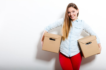 Happy woman moving into house carrying boxes.