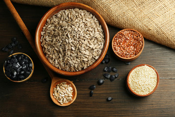 Peeled sunflower, flax and sesame seeds on wooden table background, closeup