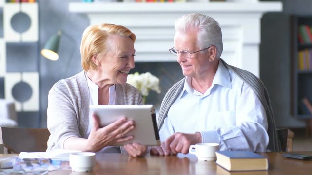 elderly happy couple working on tablet in modern apartment