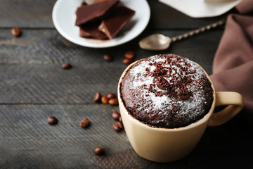 Chocolate fondant cake in cup on wooden background