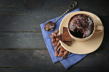 Chocolate fondant cake in cup on wooden background