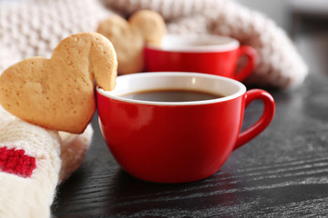 Heart shape cookie on cup of coffee on wooden table closeup