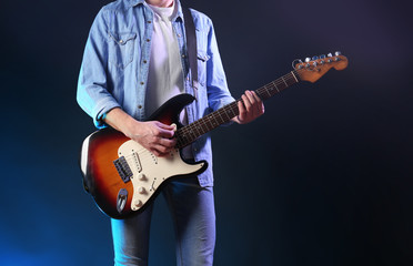 Obraz premium Man with guitar on dark foggy background