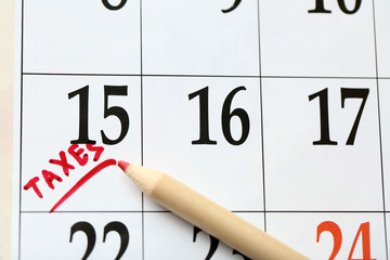 A red tax mark in the calendar on date of 15th with a pencil, close up