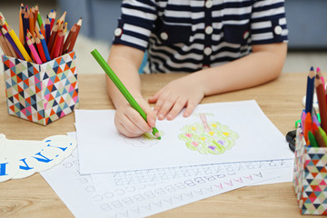 Little girl learning to draw at the table