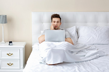 Man lying in bed with his laptop