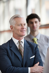 portrait of senior businessman as leader  with staff in backgrou