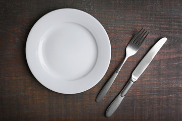 Empty plate with silver cutlery on background