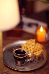 Glass cup of coffee with waffles on dark table