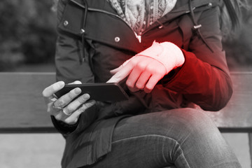 Woman with a injured wrist using a smartphone feeling pain.