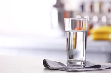 Keuken spatwand met foto Glass of pure water on kitchen table © Africa Studio