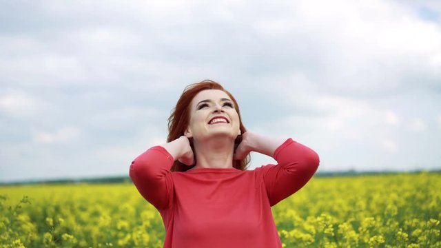 Happy red girl looking on the sky, smiling in the rape field 4k