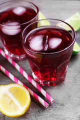 Glasses of red soda water and sliced lemon on wooden table