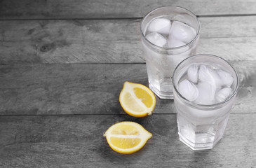 Glasses of water and sliced lemon on wooden table