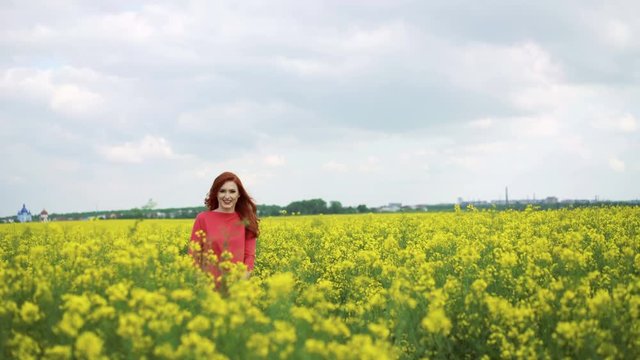 Pretty girl in the rape field walking and smiling to sky in 4k