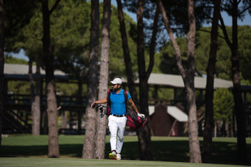 golf player walking and carrying bag