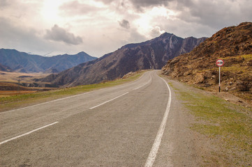 Driving on an empty asphalt road with sign towards the mountains