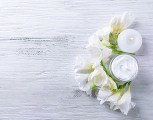 Obraz na płótnie Canvas Moisturizing cream and flowers on white wooden background