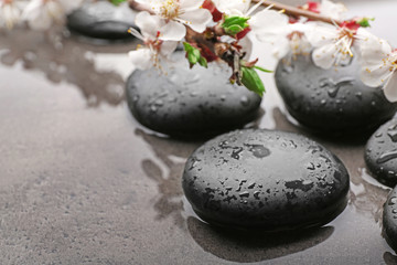Beautiful spa composition with wet stones and flowers on grey background