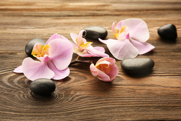 Fototapeta na wymiar Spa stones and orchid flowers on wooden background