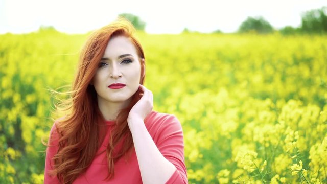 Pretty girl in the rape field and sky background smiling to the camera in 4k