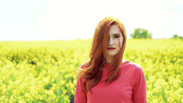 Girl in the rape blossom and sky horizon smiling to the camera, wind blow 4k
