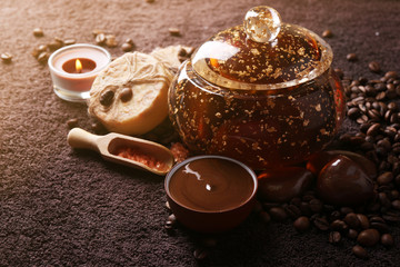 Composition of soap, chocolate in bowl and coffee beans on brown towel background