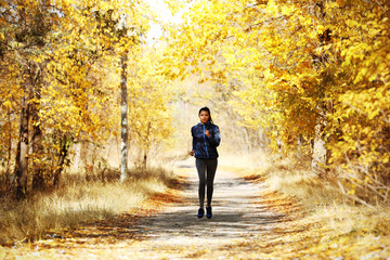 Young beautiful woman jogging in autumn park