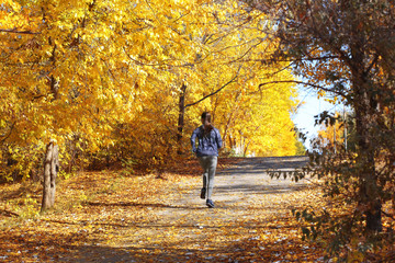 Fototapeta premium Young beautiful woman jogging in autumn park