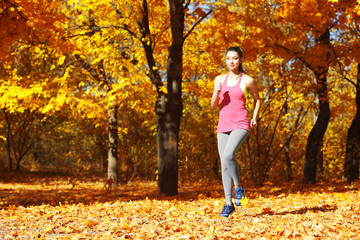 Young beautiful woman jogging in autumn park