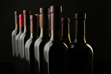 Wine bottles in a row on black  background, close up
