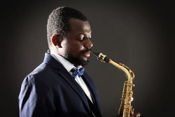 Obraz na płótnie Canvas African American jazz musician playing the saxophone on grey background