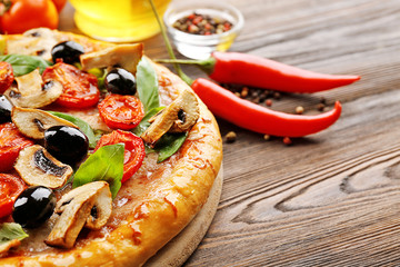 Delicious tasty pizza with ingredients on wooden table
