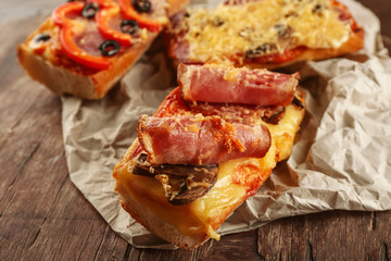 Hot pizza baguette with bacon and cheese on wooden table