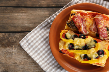 Hot pizza baguettes with paprika, bacon, olives and cheese on wooden table