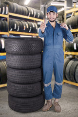 Fototapeta na wymiar Mechanic shows OK sign in the tires shop