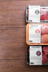 Packed pieces of chicken, pork and beef meat on wooden background