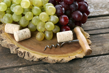 Wine corks and tailspin with bunch of grapes on wooden background