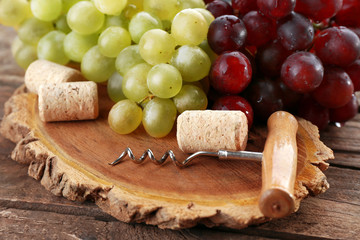Wine corks and tailspin with bunch of grapes on wooden background
