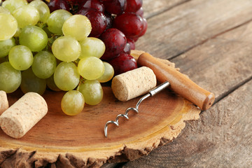 Wine corks and tailspin with bunch of grapes on wooden background
