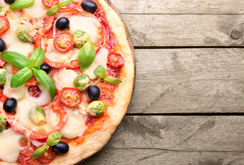 Delicious pizza with cheese and vegetables on wooden background