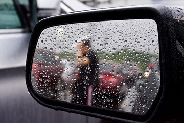 Looking into a car side mirror on a rainy day