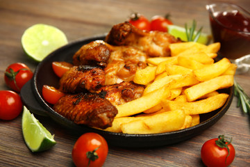 Baked chicken wings with French fries on wooden table