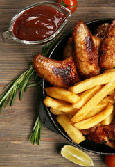Baked chicken wings with French fries on wooden table