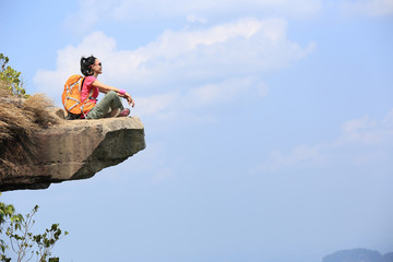 young woman backpacker hiking on seaside mountain peak