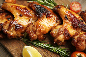 Baked chicken wings with tomatoes and rosemary on cutting board