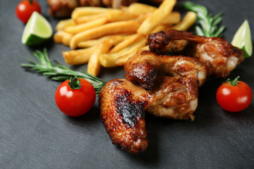 Baked chicken wings with French fries on slate plate